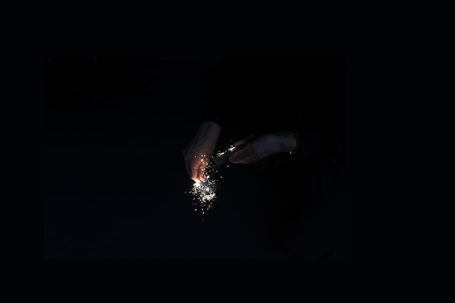 Hands ignite golden sparks using a flint in the dark, untitled HD wallpaper