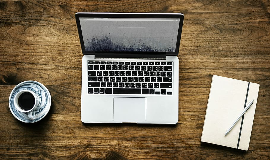 MacBook Pro beside white-and-black ceramic teacup and saucer and white tablet folio case HD wallpaper