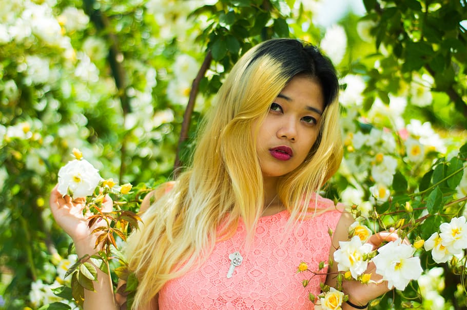 woman standing between white petaled flower, woman wearing pink shirt standing near tree and holding white petaled flower HD wallpaper