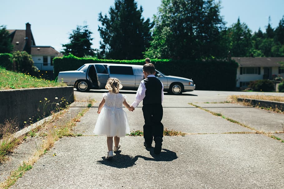 boy and girl walking on gray road during daytime, boy holding girl's hand walking towards limousine HD wallpaper