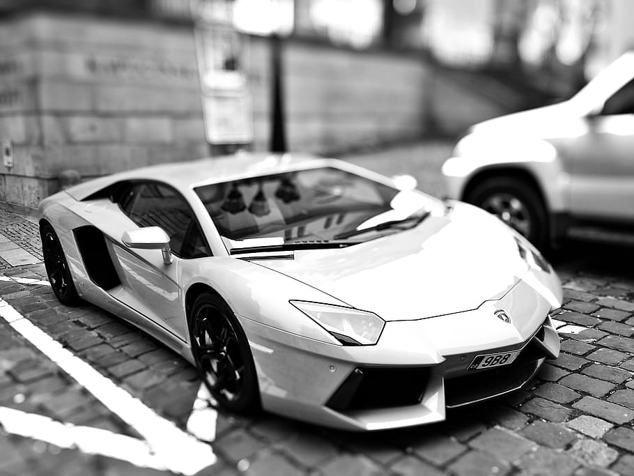 grayscale and tilt shift photography of Lamborghini Aventador coupe on parking lot