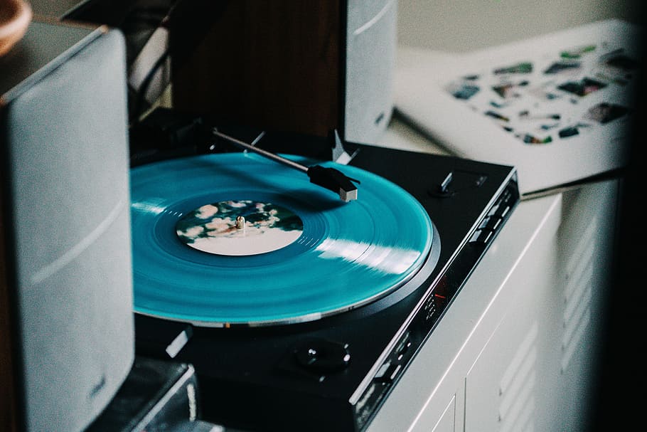 close-up photography of turned-on vinyl record player, black turntable playing green vinyl record