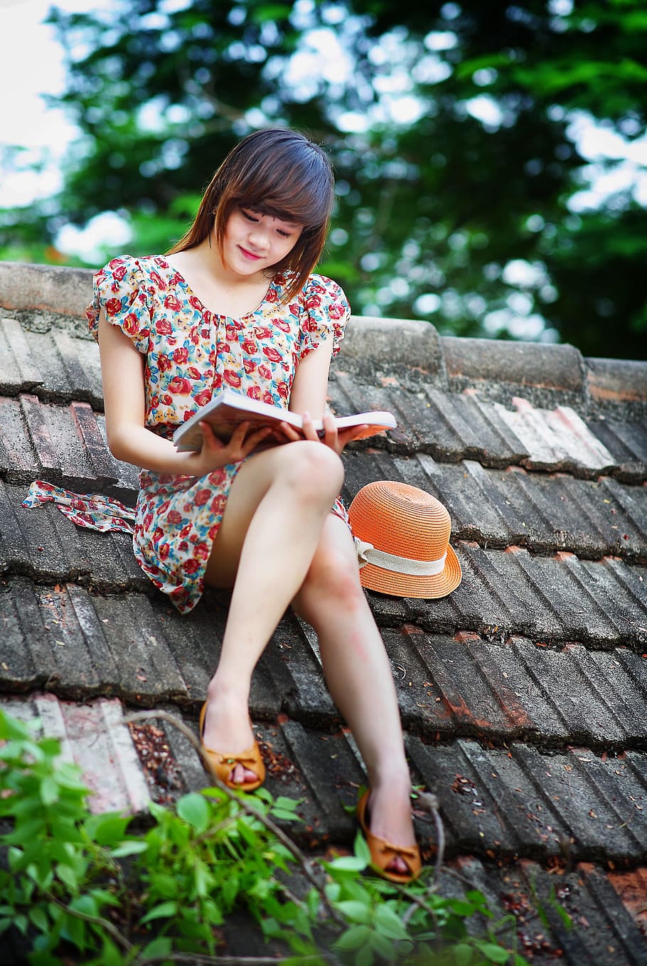 woman wears pink and multicolored floral cap-sleeved dress on the top of the roof