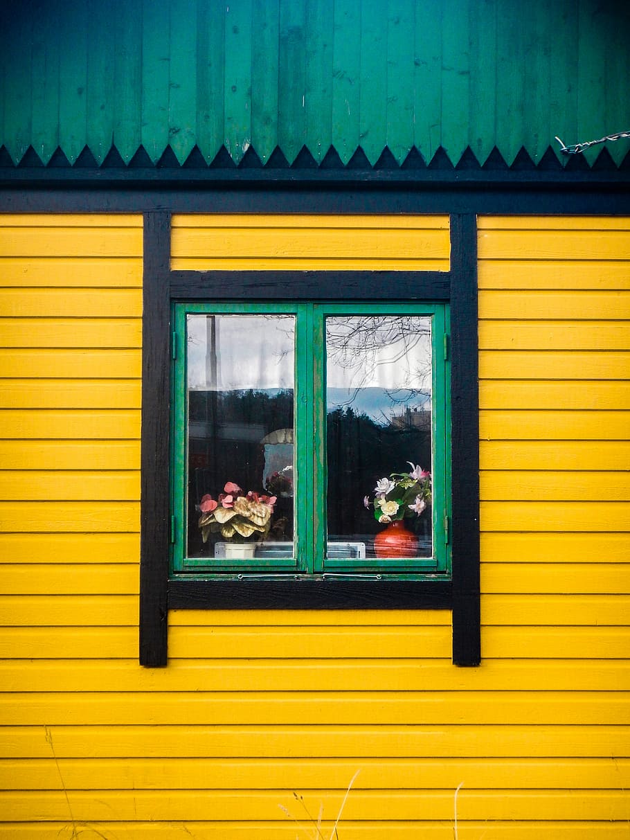 yellow and black painted house with green framed glass window, green and black window on yellow wall