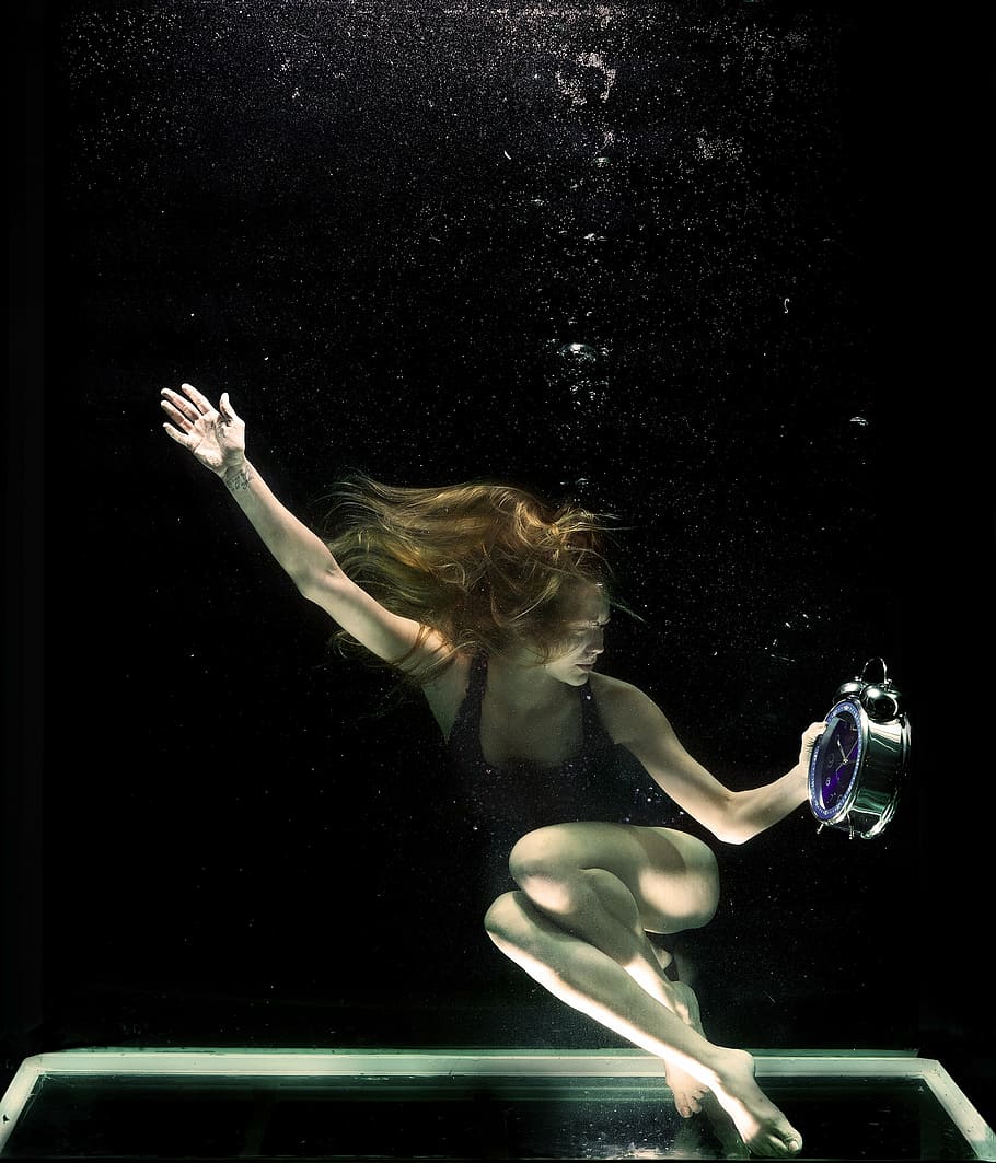 woman holding silver analog alarm clock, underwater, model, fine arts