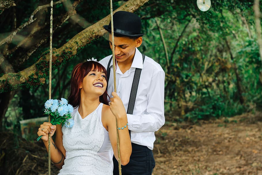 couple during pre-nuptial pictorial, woman riding swing in front of man