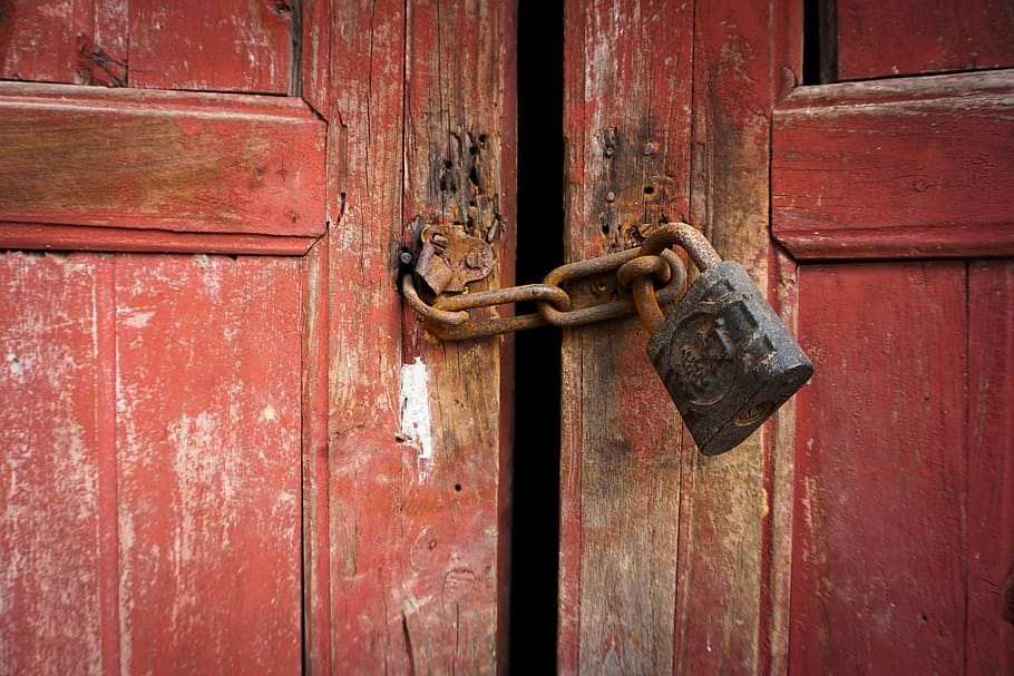 closeup photo of rusted black and brown padlock with rusted brown keychain locked on brown wooden door panel HD wallpaper