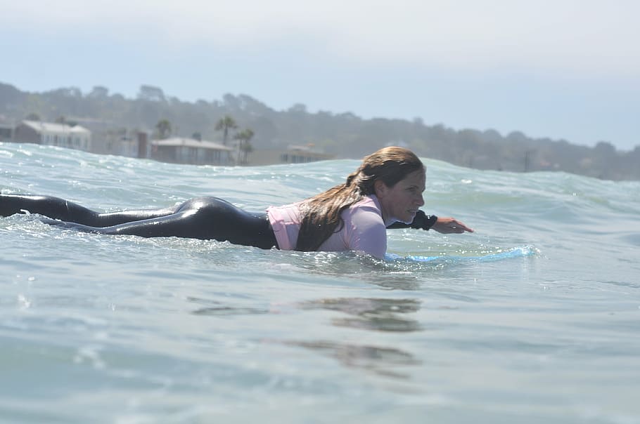 woman swims on body of water, surfing, paddling, surfer girl