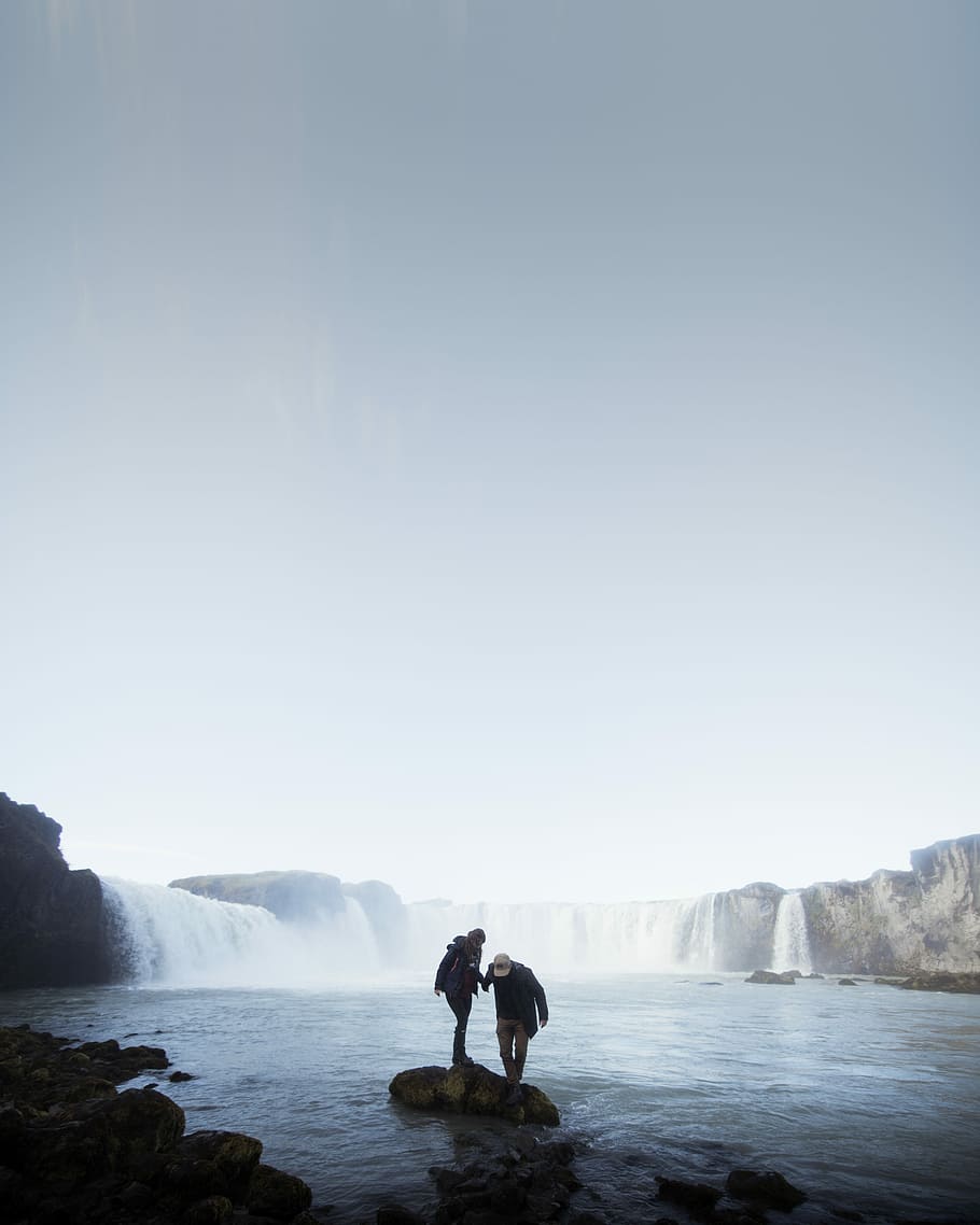 Godafoss in Autumn, two person standing on rocks surrounded with water HD wallpaper