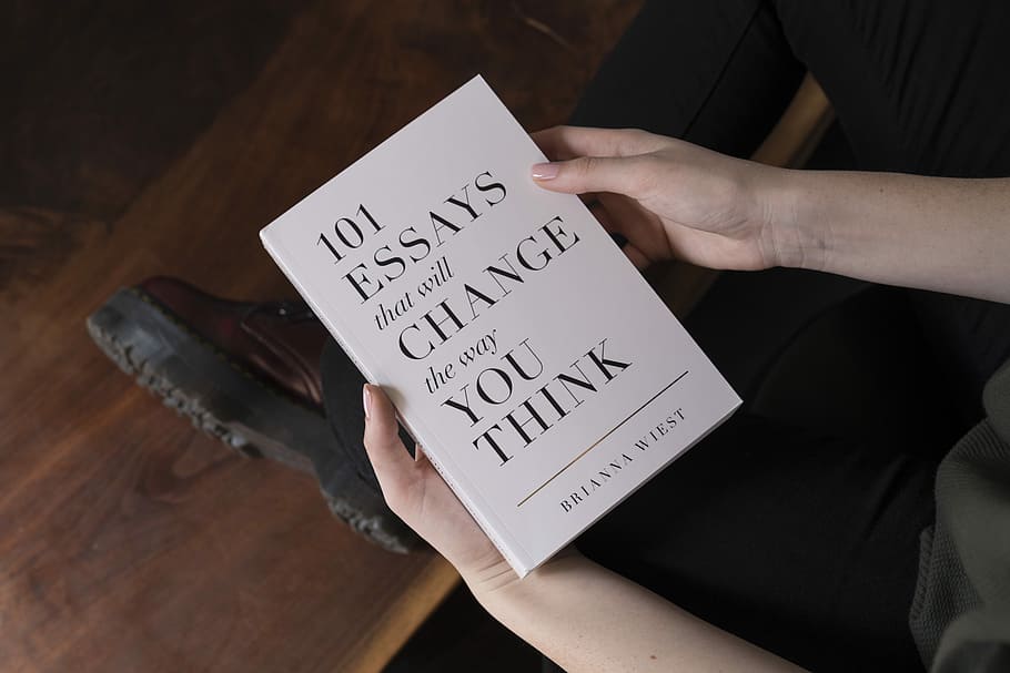 person holding 101 Essay that will Change the way you Think book, person holding 101 Essays That Will Change The Way You Think