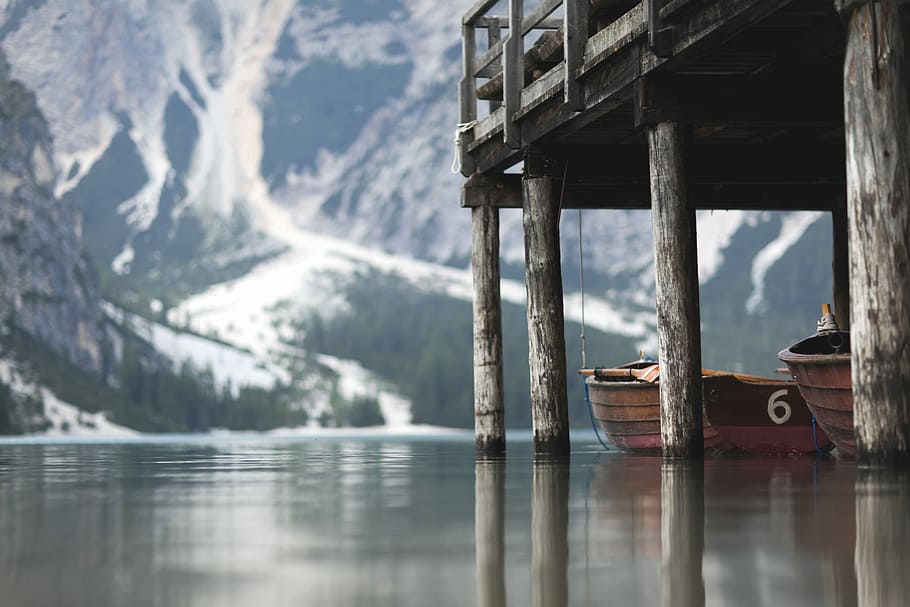 two brown wooden canoe under dock with mountain in distance, architectural photography of bridge HD wallpaper