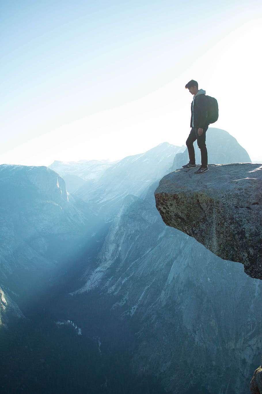 man standing on cliff, person standing on the top edge of mountain cliff