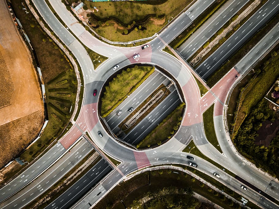 aerial photography of vehicles running on vehicle intersection route at daytime, aerial photography of round concrete road