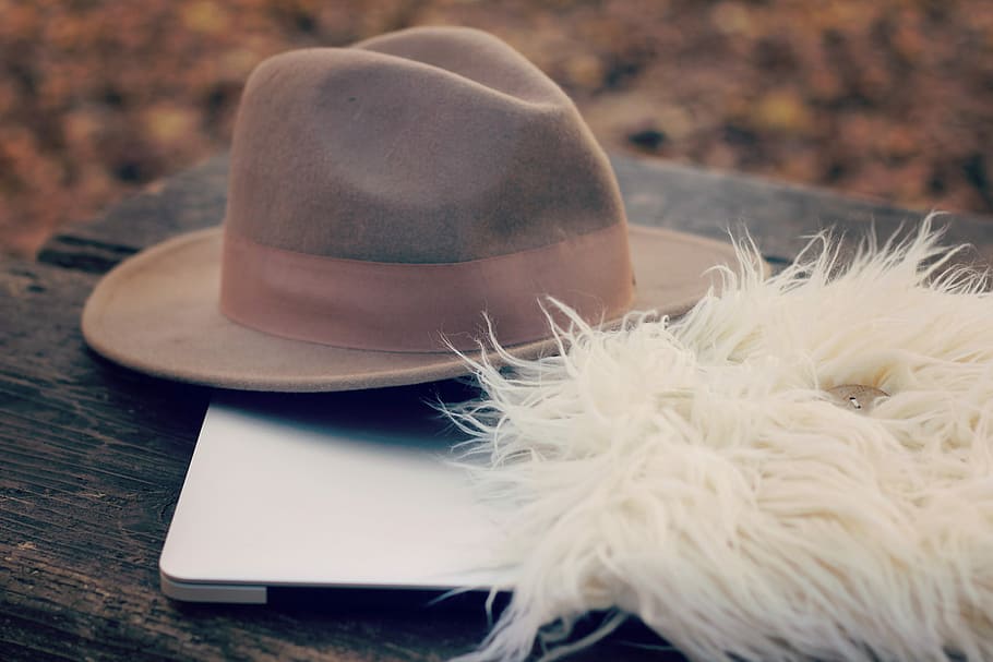 grey fedora hat on silver laptop beside a white fur textile, fashion HD wallpaper