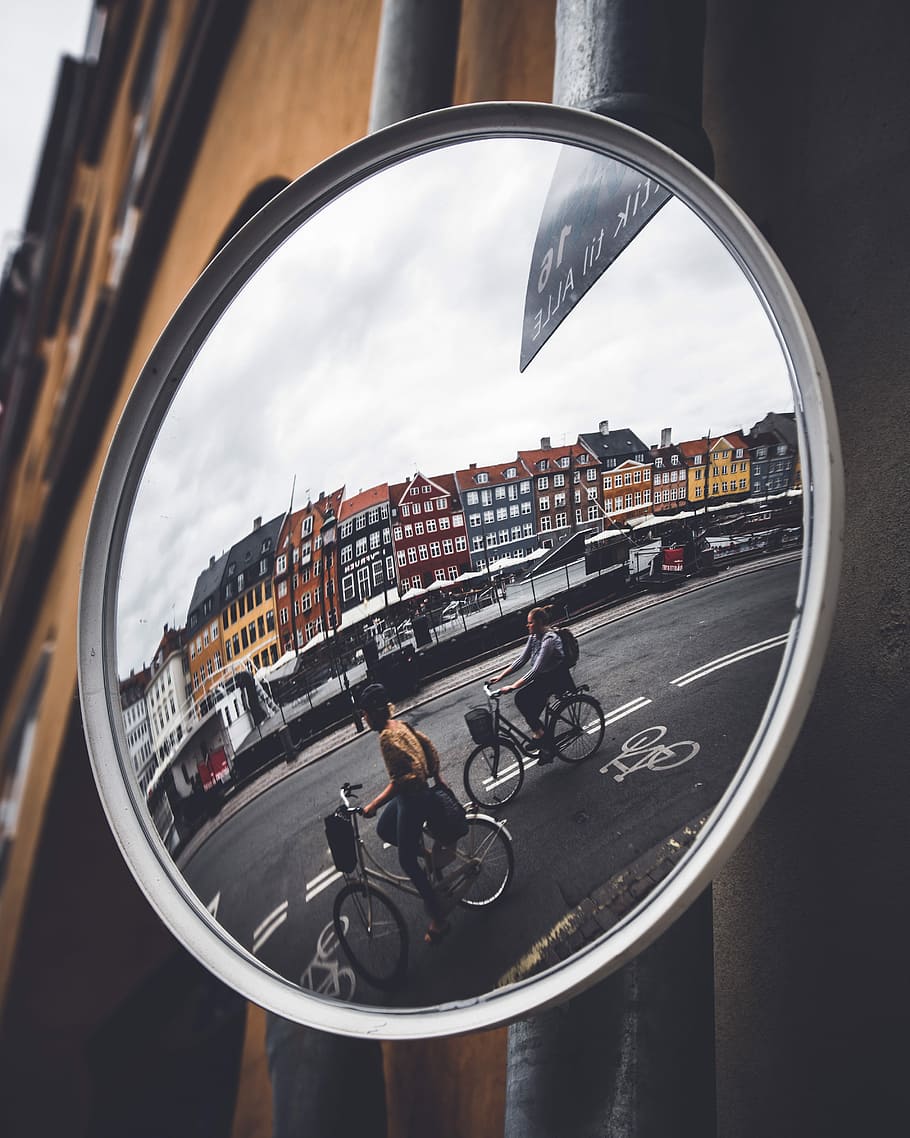 City reflection, reflection of two person riding on bike on clear glass mirror HD wallpaper
