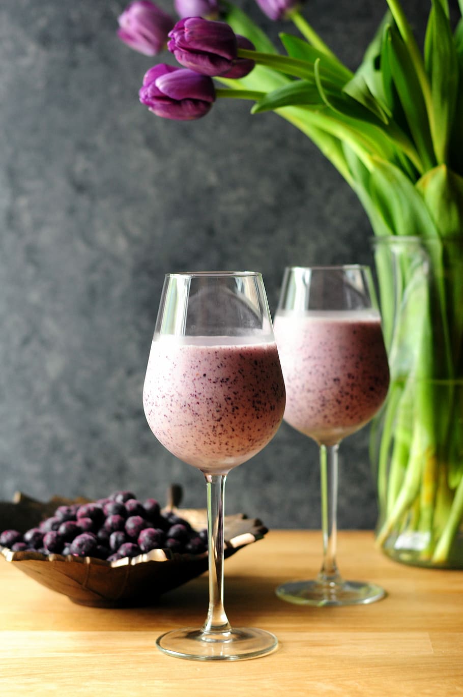two berry shake on drinking glasses, milkshake in clear wine glasses on brown wooden surface