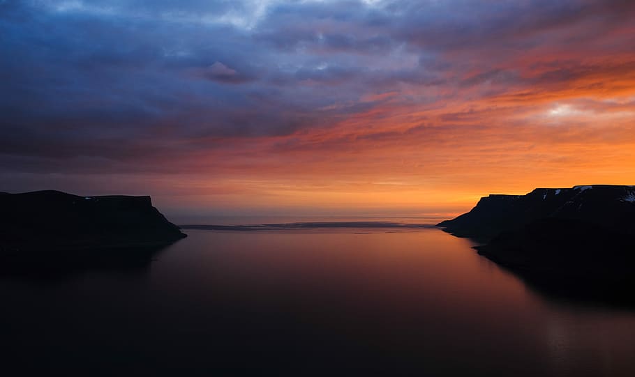 body of water under orange sunset, body of water between mountain HD wallpaper