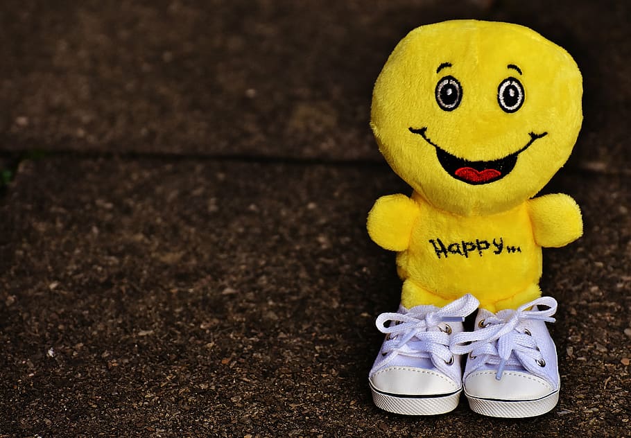selective focus of yellow emoji plush toy, smiley, laugh, sneakers