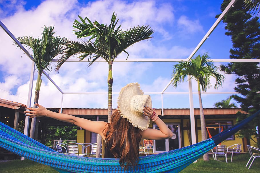 woman in white summer hat sitting on blue hammock during daytime HD wallpaper