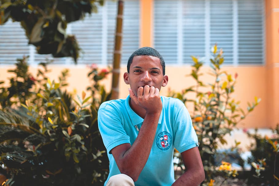 man sitting in front of green plants during daytime, man wearing blue polo shirt HD wallpaper