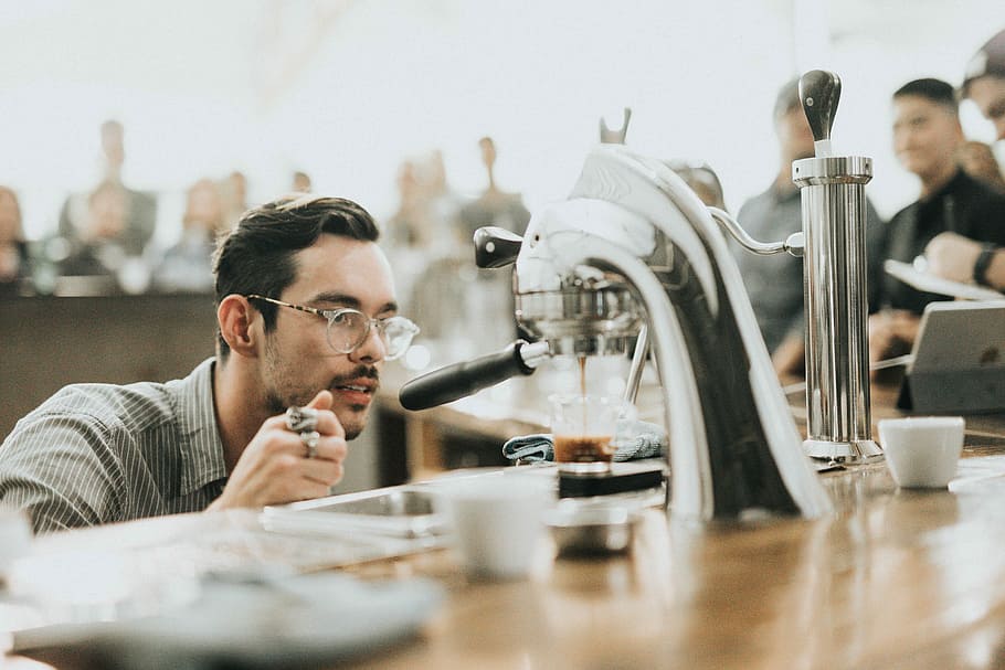 man looking at coffee in coffeemaker, photo of man looking glass pouring espresso maker