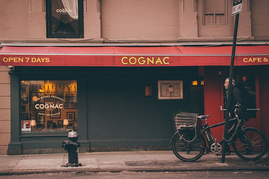 man walking in front of Cognac store, Cognac store facade with black bicycle with man HD wallpaper