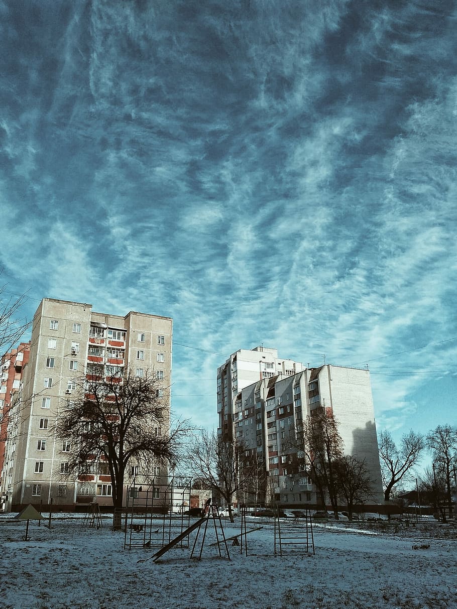 two gray and brown concrete building under black sky, black metal playground near white concrete building during golden hour HD wallpaper