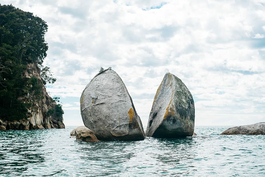 gray rock cut in half, two gray boulder on body of water at daytime