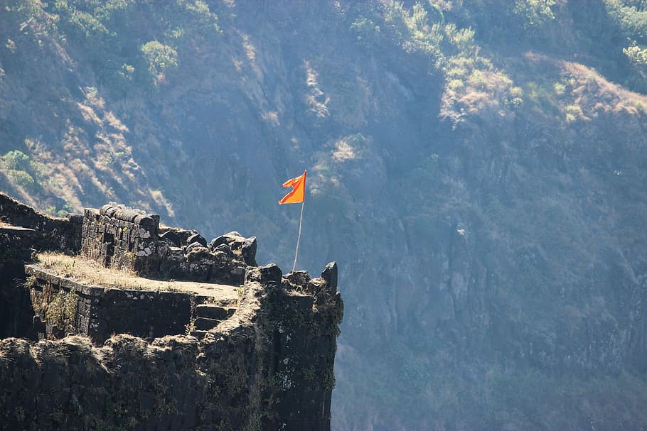 Invincible fortress, orange flag standing on cliff during daytime HD wallpaper