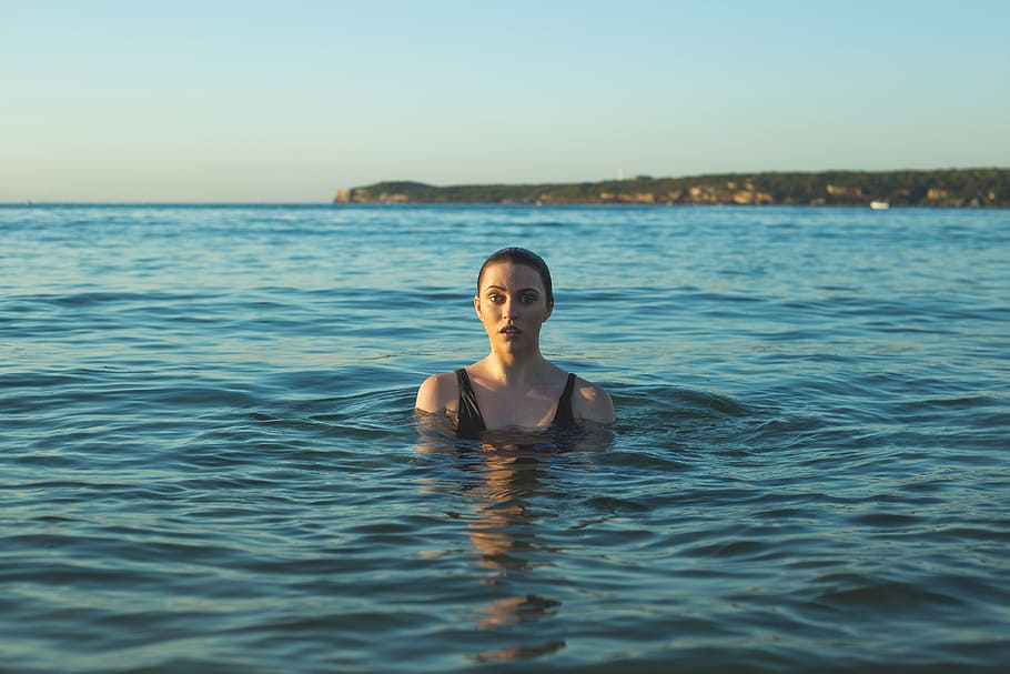 woman wearing black tank top swimming on sea at daytime, beach