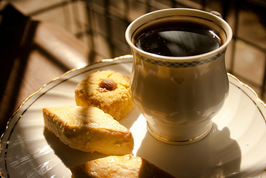 three breads beside poured cup on plate, coffee, coffee beans