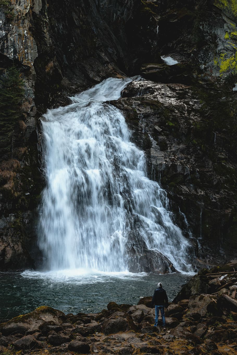 person in-front waterfalls, photo of waterfalls near rock mountain HD wallpaper