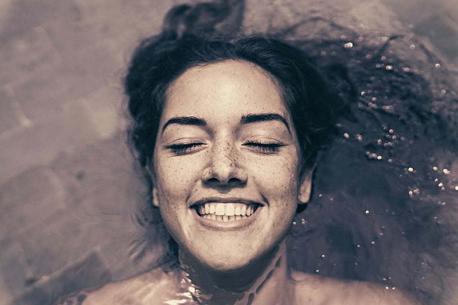 woman smiling while bathing, woman floating in water, face, portrait