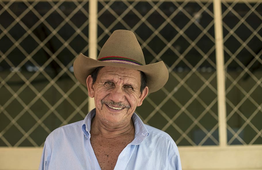 man wearing brown cowboy hat, man taking photo near screen while smiling HD wallpaper
