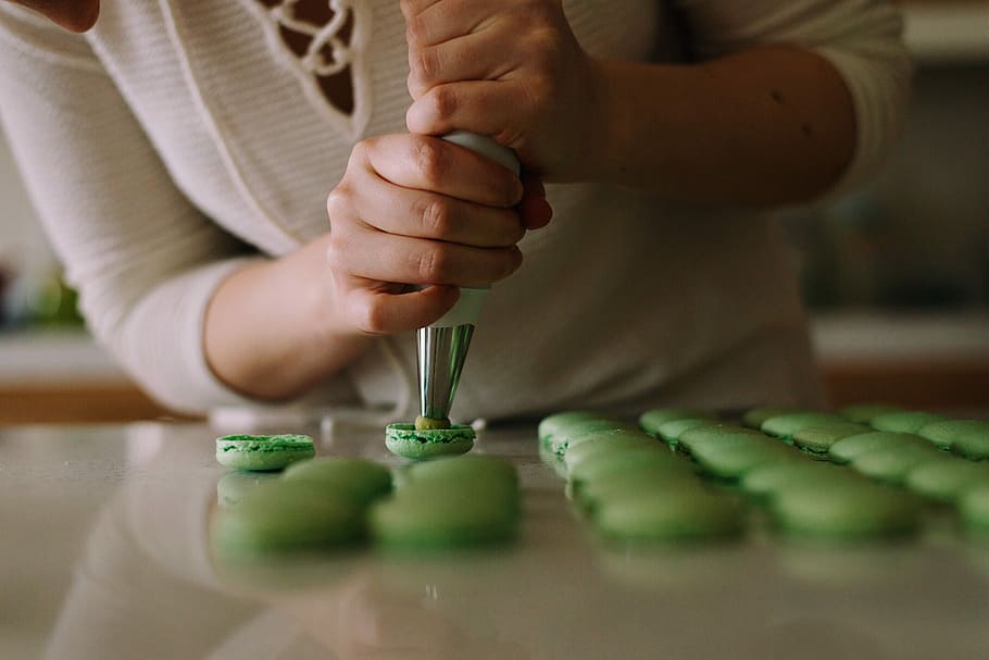 selective focus photography of woman putting icing on cupcakes, person making French macaron HD wallpaper