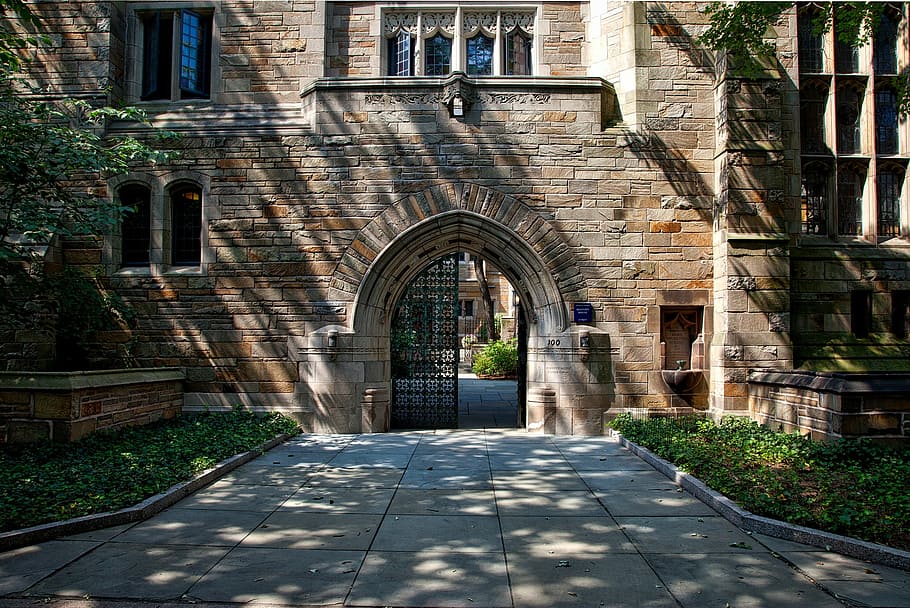 brown cladding wall building with black metal gate open, yale university