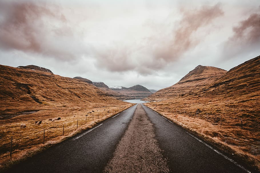 road between mountains, road between brown rock formation under brown sky HD wallpaper