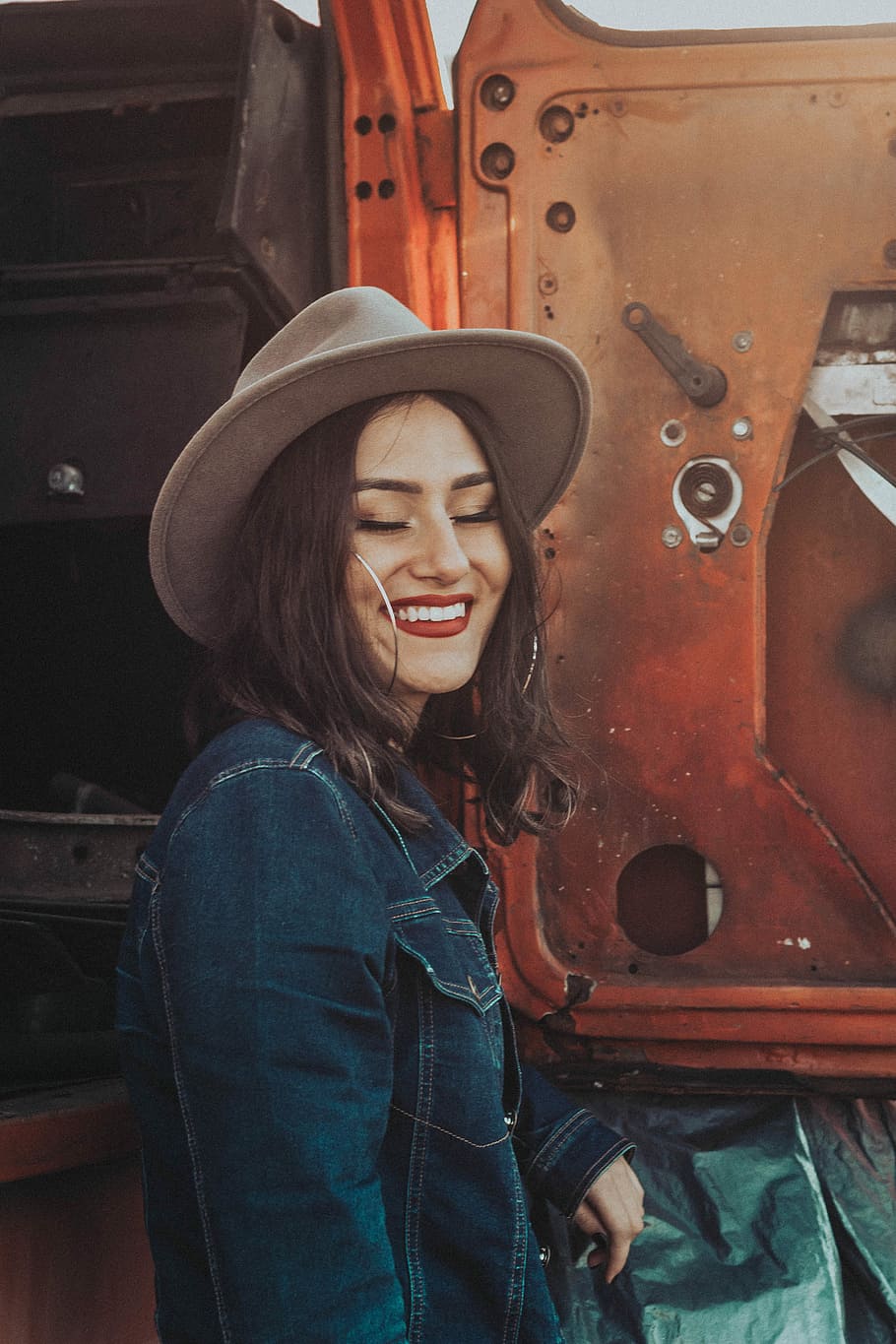 woman smiling beside tractor, woman wearing brown hat beside truck door