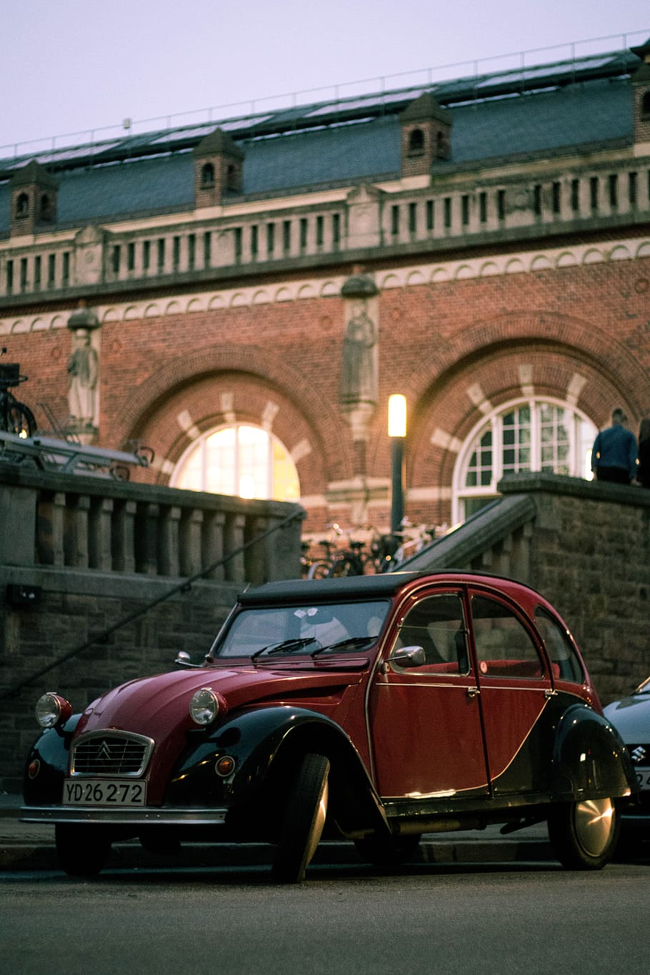 red and black Volkswagen Beetle parked beside brown building