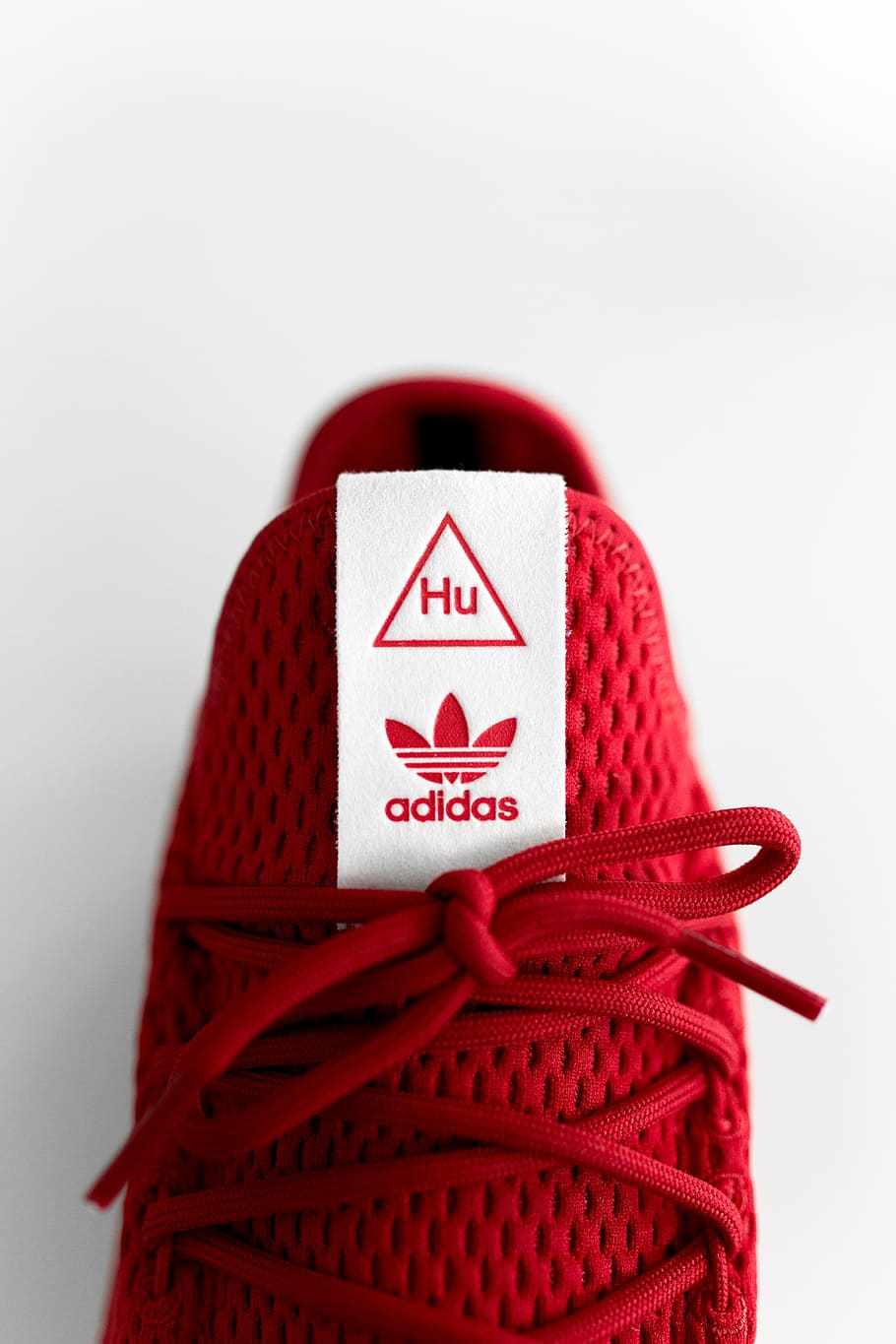 unpaired red adidas sneaker, closeup photo of unpaired red adidas Tennis HU sneaker against white background
