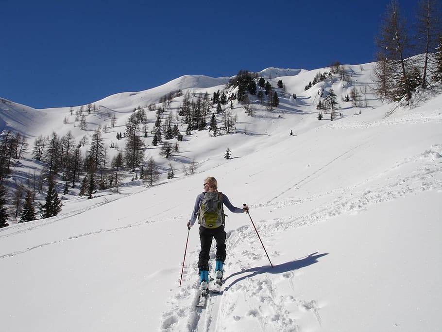 man walking on snow field, backcountry skiiing, ski mountaineering