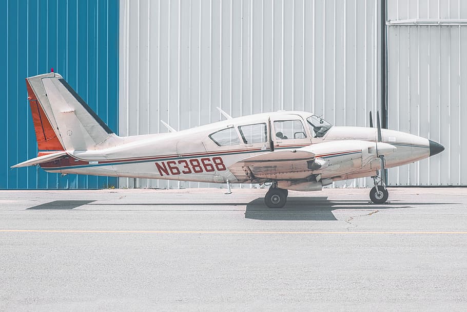 white and orange N63868 airplane parked near building during daytime, shallow focus photography of white airplane