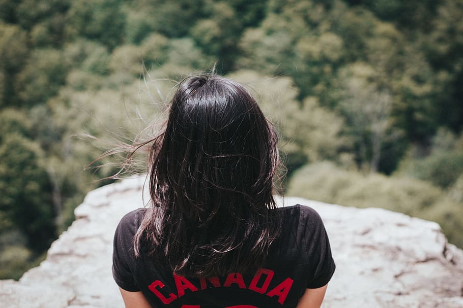 woman in black top beside on mountain cliff during daytime, woman in black Canada shirt in mountain HD wallpaper