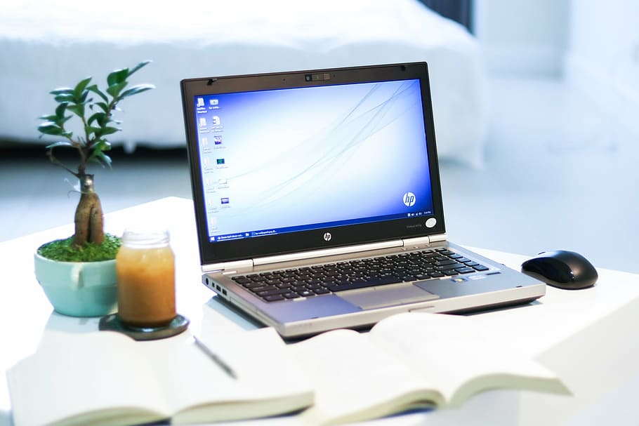 black and gray HP laptop computer on white wooden table, technology