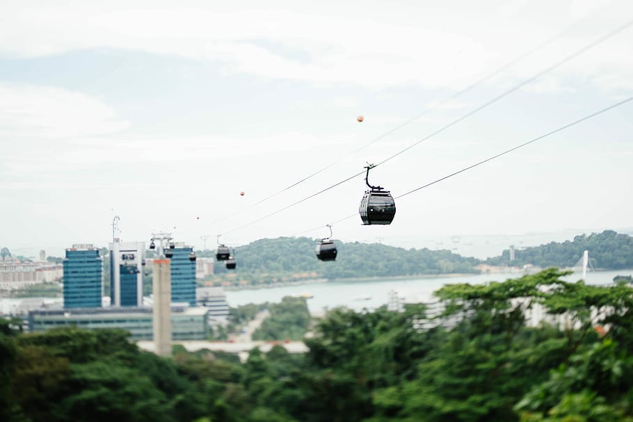 four white cable cars near blue building, assorted-color cable cars HD wallpaper