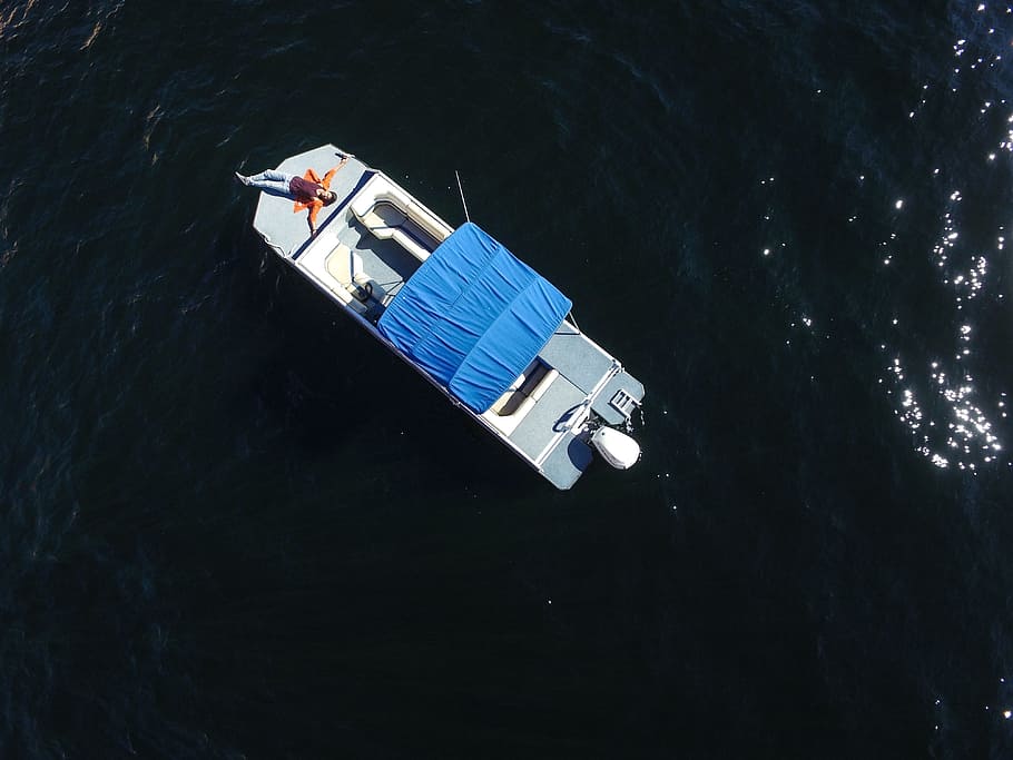 aerial photo of gray boat on body of water, person lying on boat HD wallpaper