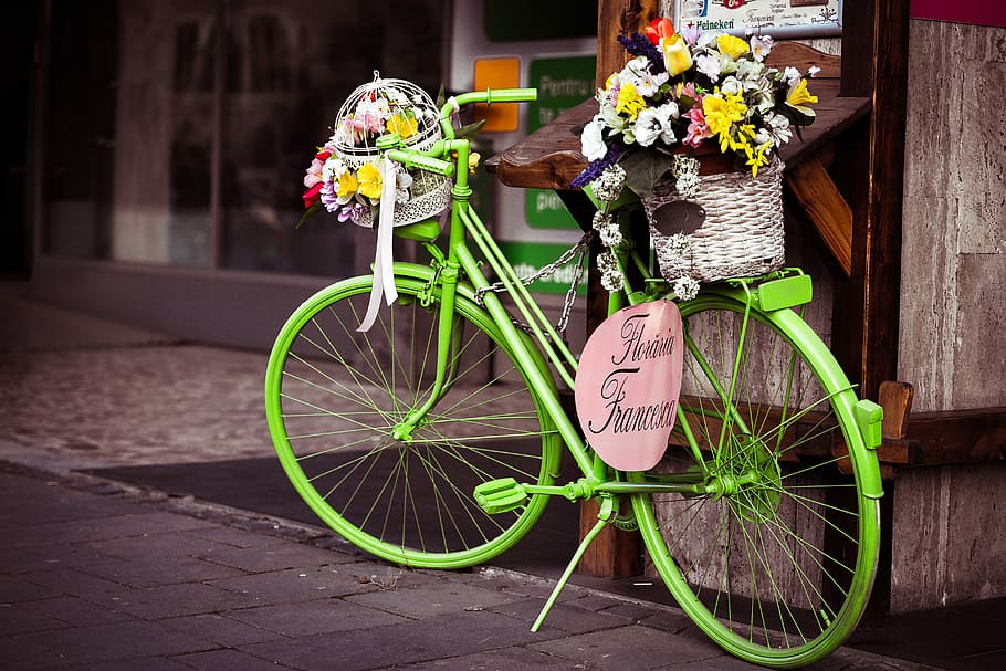 basket of petaled flower ongreen city bike, parked green commuter bike with basket of flowers