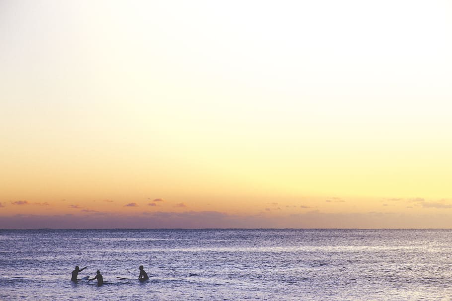 three person playing on ocean during golden hour, three person swimming in sea during sunset HD wallpaper
