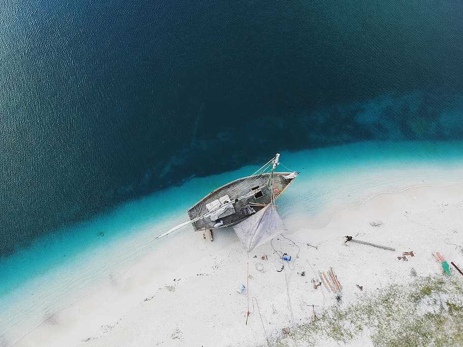 aerial photo of boat on seashore during daytime, high-angle photo of gray and white fishing boat on seashore during daytime