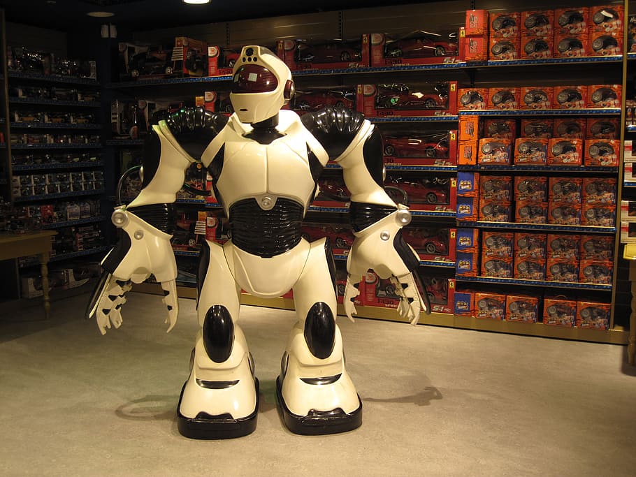 white and black robot standing next to grey muscle rack, toy HD wallpaper